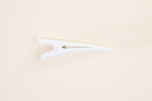 Glossy white TopBun hair clip against neutral background