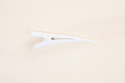Glossy white TopBun hair clip against neutral background