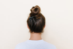 Black matte TopBun hair clip shown holding a high bun in brunette hair